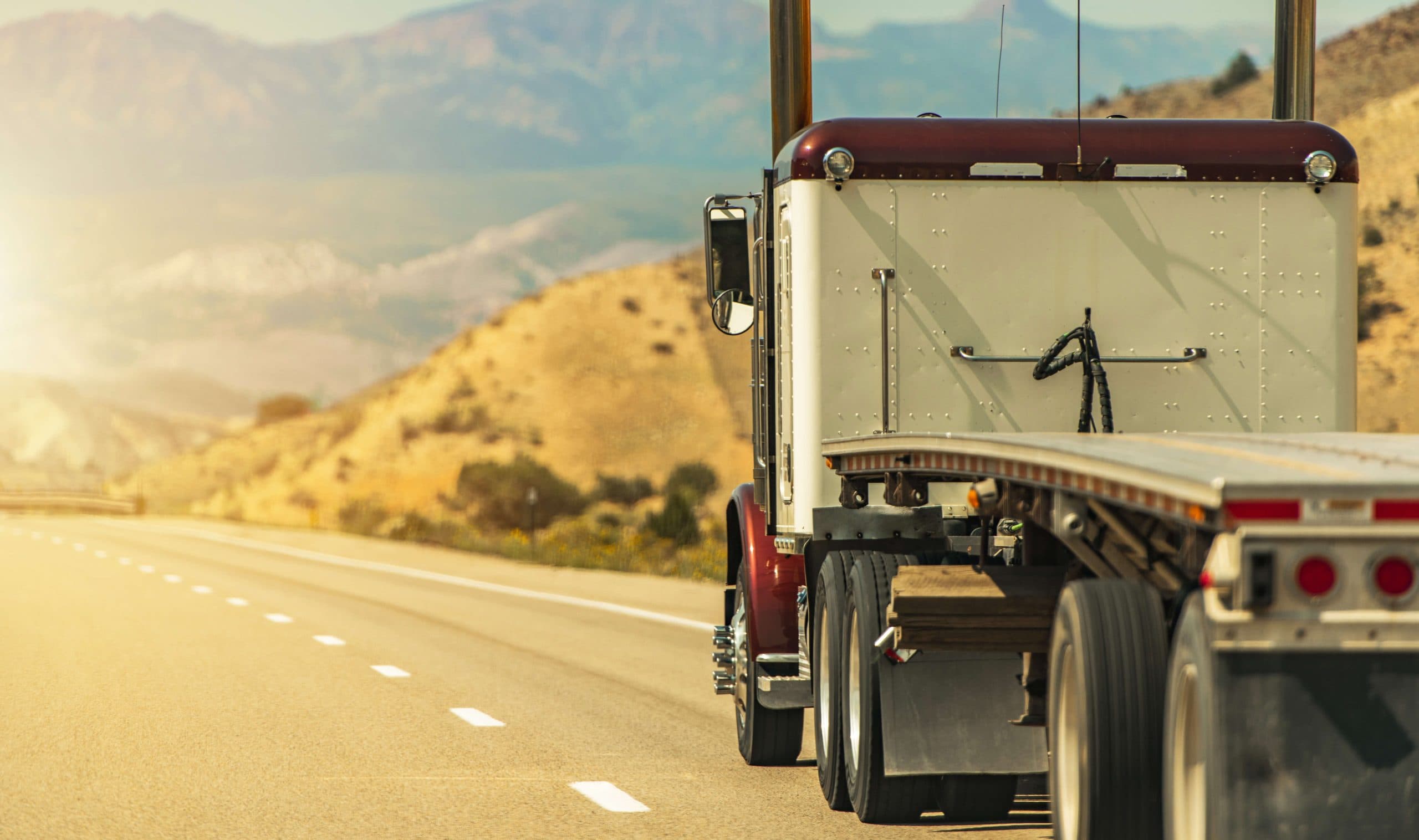 Flatbed truck and open trailer on a highway